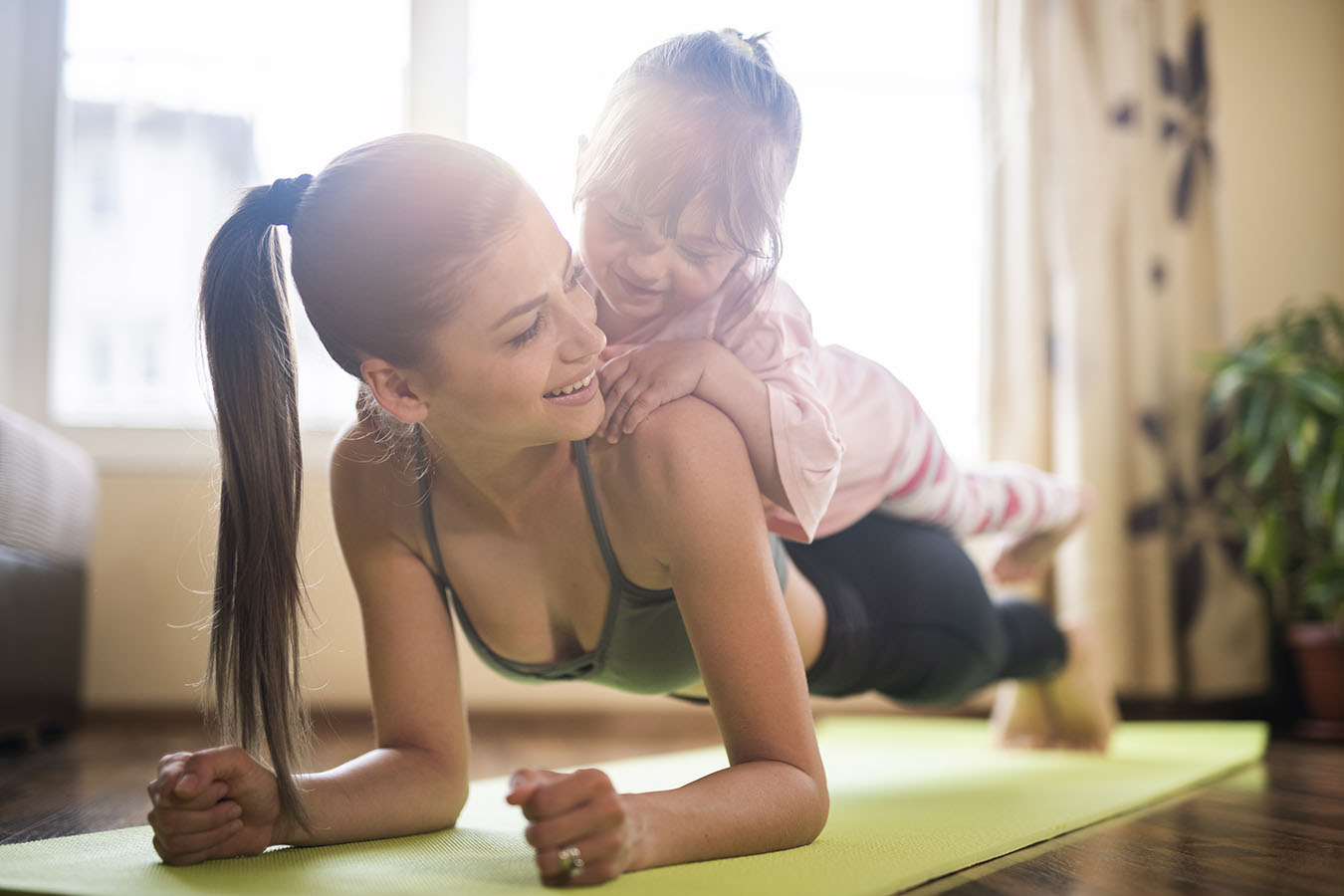 mid-adult-mother-practicing-yoga-with-toddler-daughter-on-top-of-her-beautiful-mother-and-daughter-training-home-workout