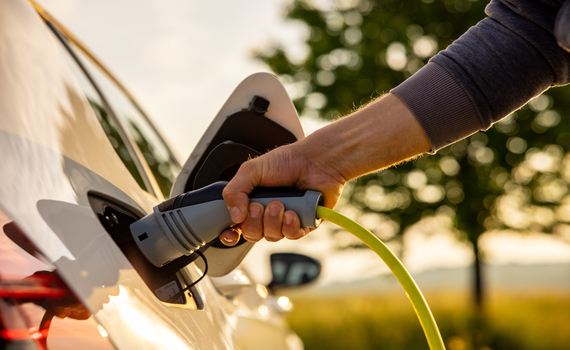 man-inserts-a-power-cord-into-an-electric-car-for-charging-in-the-nature