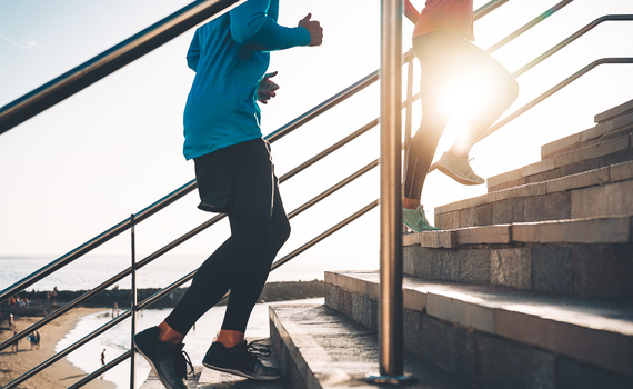 view-of-runners-legs-training-outdoor-young-couple-doing-a-workout-session-on-stairs-next-the-beach-at-sunset-healthy-people-jogging-and-sport-lifestyle-concept