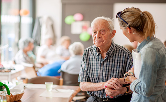 Uma mulher dá instruções a um homem idoso com doença de Alzheimer. 