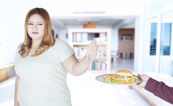 Uma jovem que rejeita a fast food (hambúrguer e batatas fritas) graças aos prebióticos que influenciam as suas escolhas alimentares. 