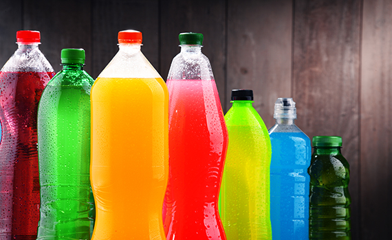 Bebidas açucaradas de diferentes cores e sabores em garrafas de plástico.