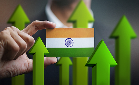 Um homem segura um cartão com as cores da bandeira indiana. No fundo, as setas verdes representam o crescimento económico da Índia. 