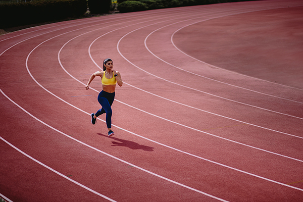Um jovem atleta a correr numa pista de corrida.
