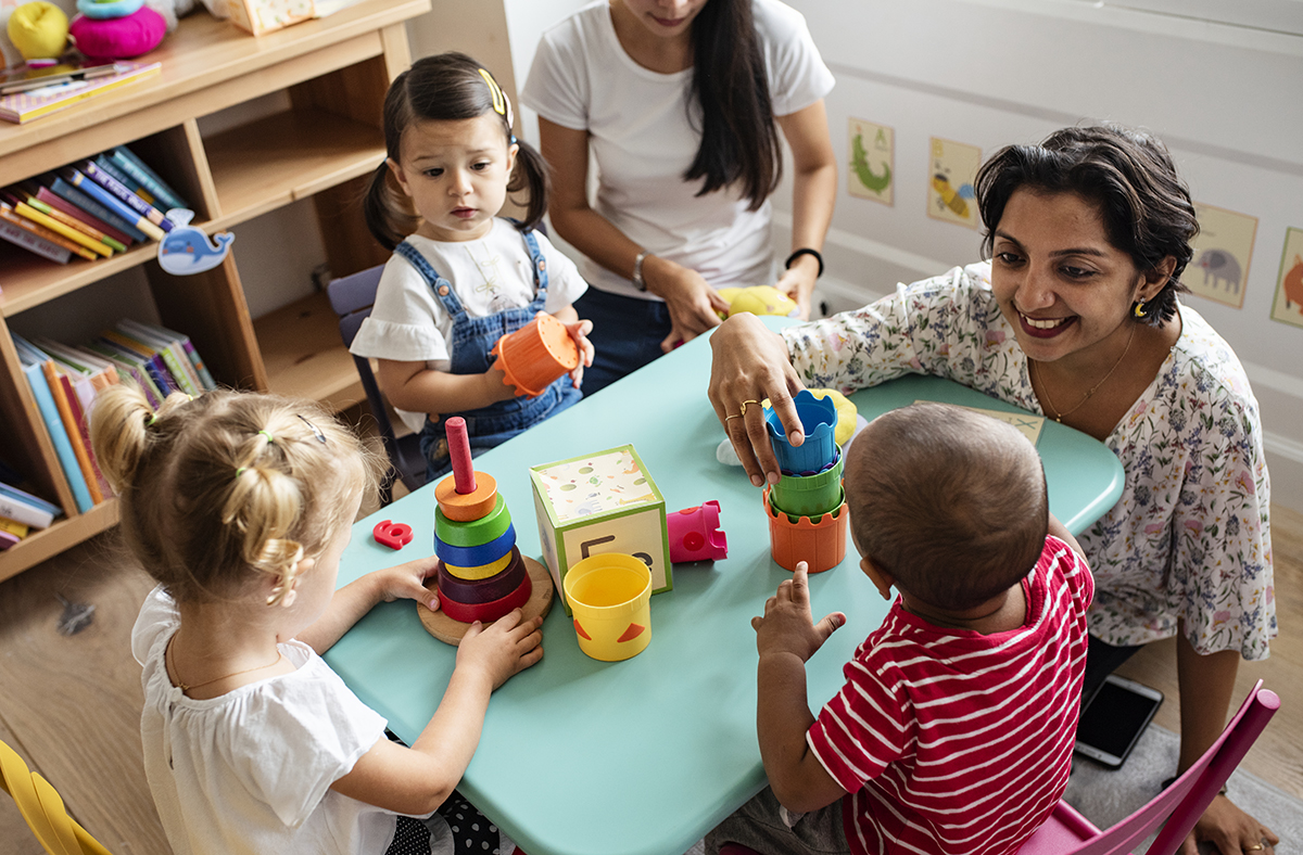 Crianças em idade pré-escolar brincando com seu professor. 