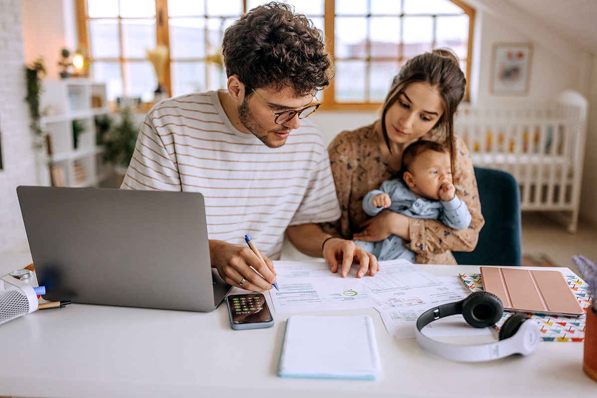 Um marido analisa os dados do orçamento com sua esposa, que está segurando o bebê. 