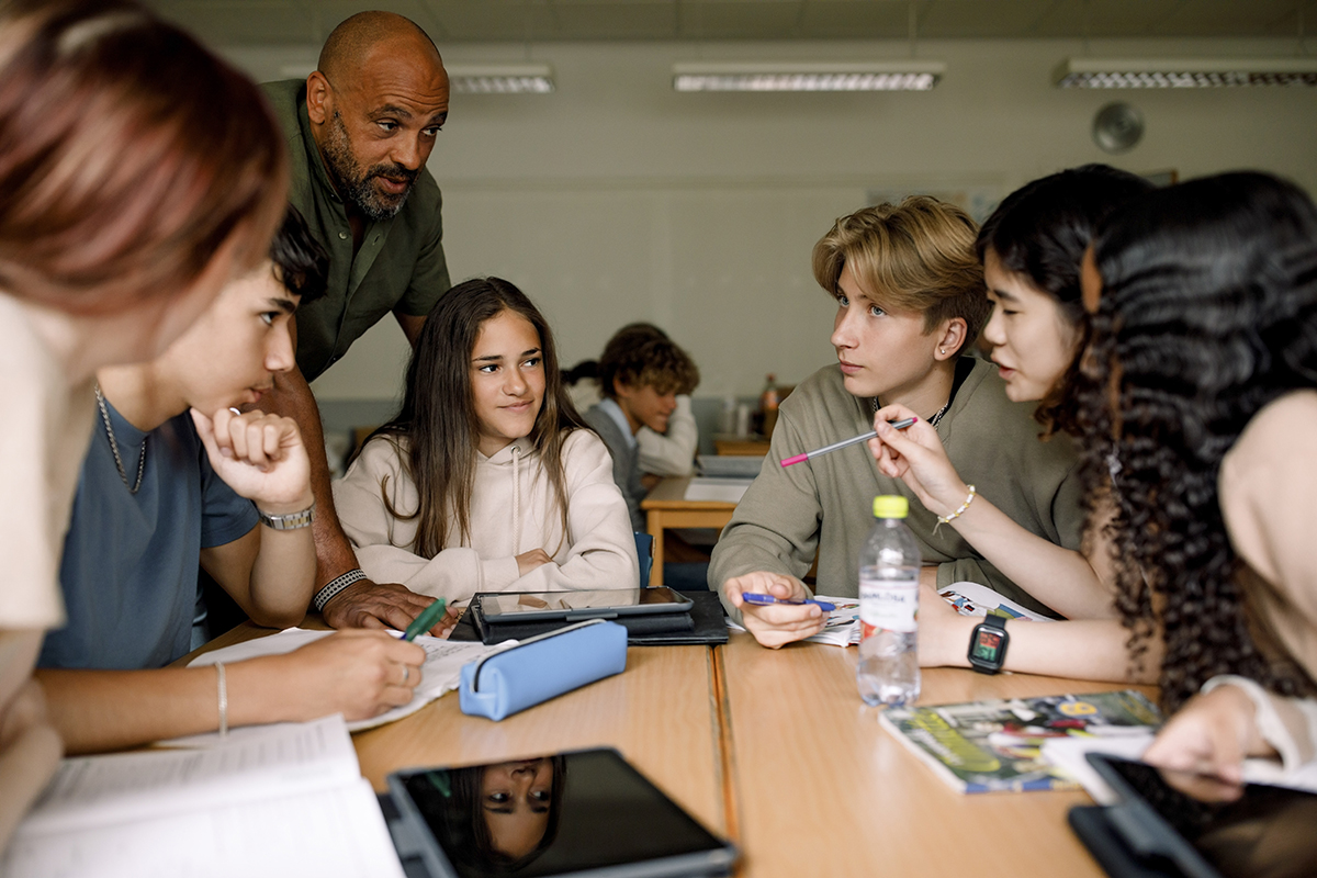 Grupo de jovens fazendo trabalho em grupo na sala de aula. 