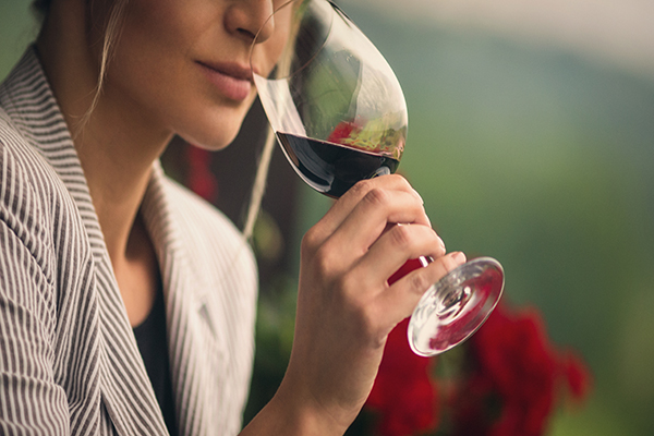 Uma mulher jovem bebe um copo de vinho tinto, rico em flavonóides, para evitar o risco de demência.