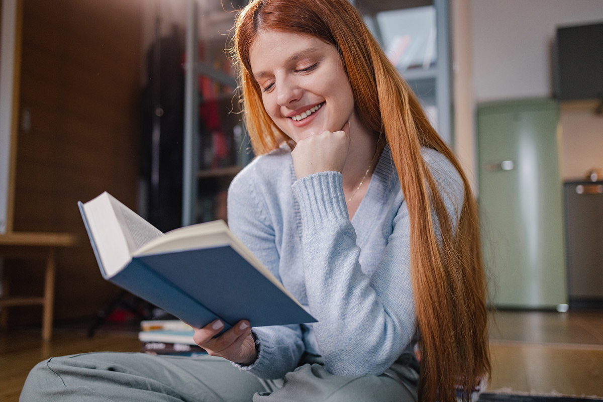 Menina de cabelos vermelhos lendo um livro. 