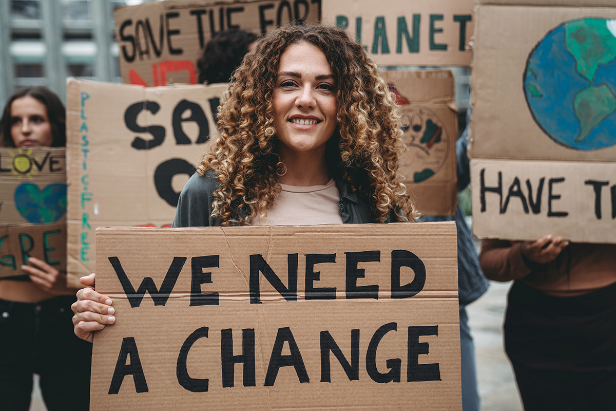 Retrato de uma garota segurando uma placa com o texto “save our planet” (salve nosso planeta).