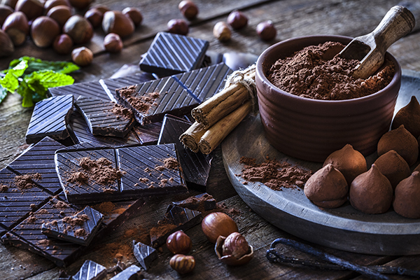 Chocolate preto em barras e em pó numa mesa de madeira. 