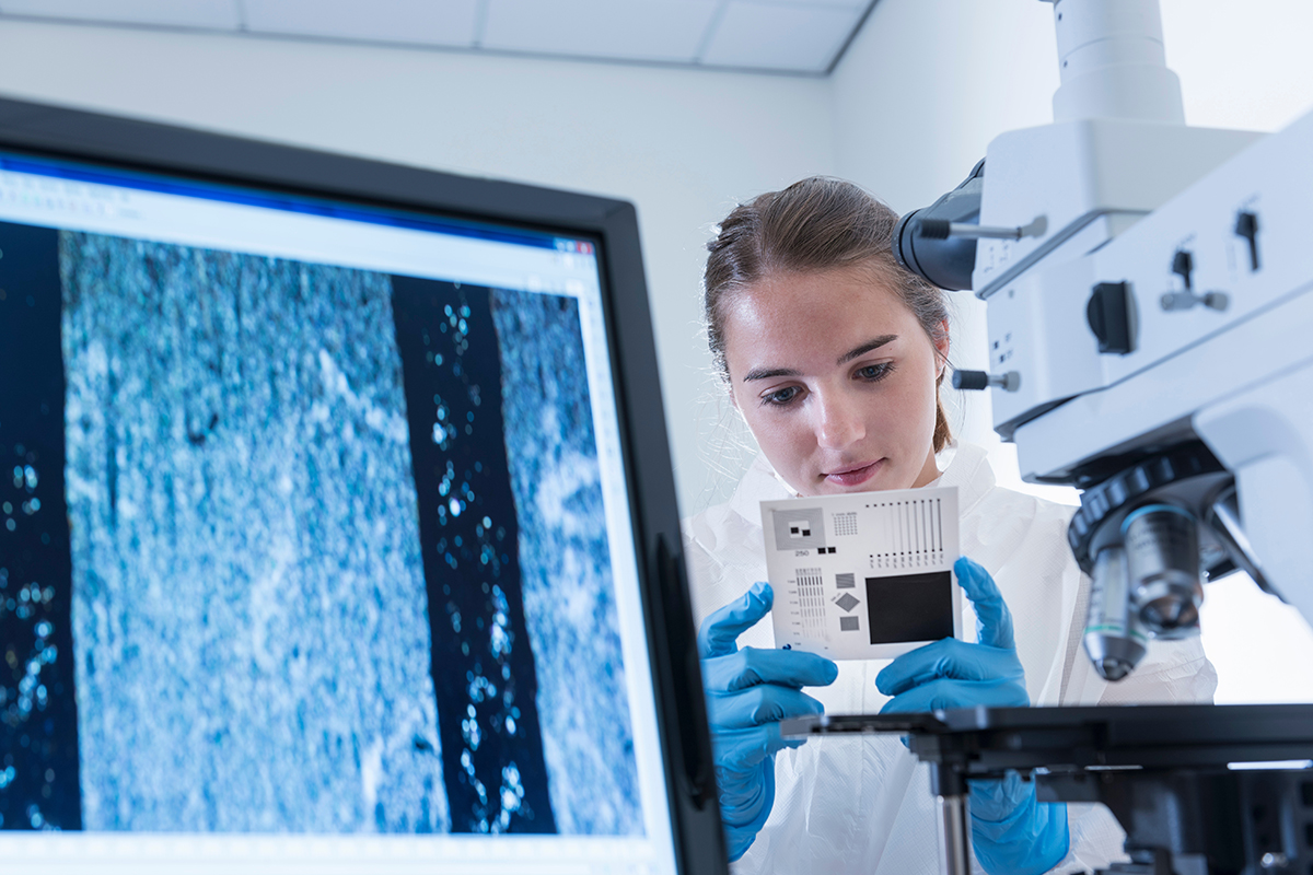 mulher-cientista-inspeciona-amostra-de-grafeno-com-microscópio-em-fábrica-de-processamento-de-grafeno