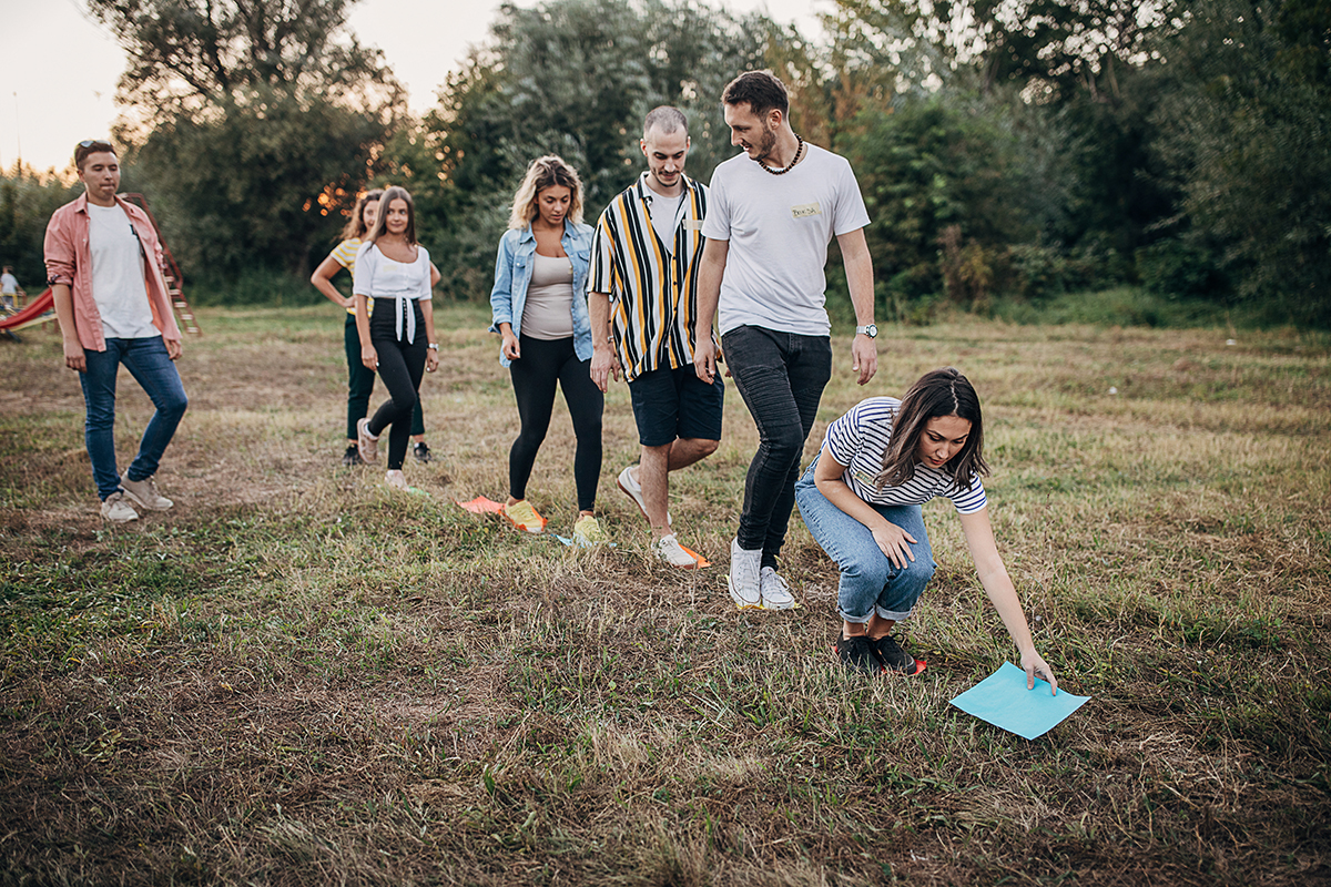 Grupo de jovens, homens e mulheres, se divertindo e jogando jogos de formação de equipes na natureza.