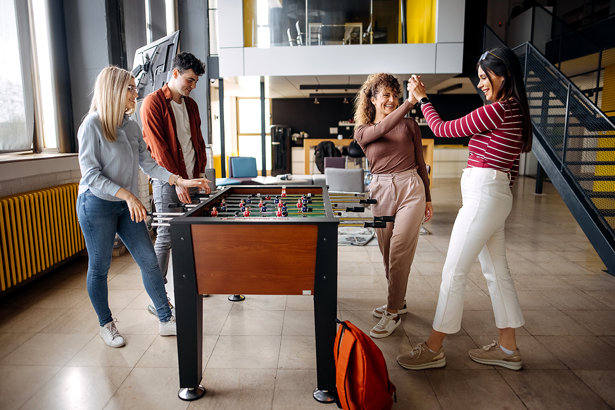 Design inclusivo: Funcionários jogando em uma mesa de futebol de mesa.