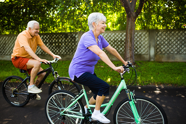 Dois idosos a fazer exercício físico (andar de bicicleta) para melhorar a sua saúde.