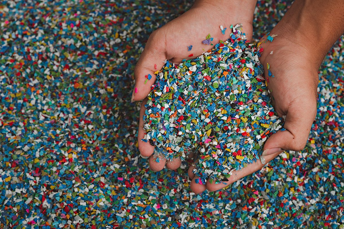 Logística reversa - imagem de mãos segurando pellets de plástico branco transparente, matéria-prima para vários processos de fabricação.