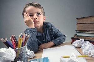Bored and fed boy up doing his homework Cómo acabar con una educación aburrida