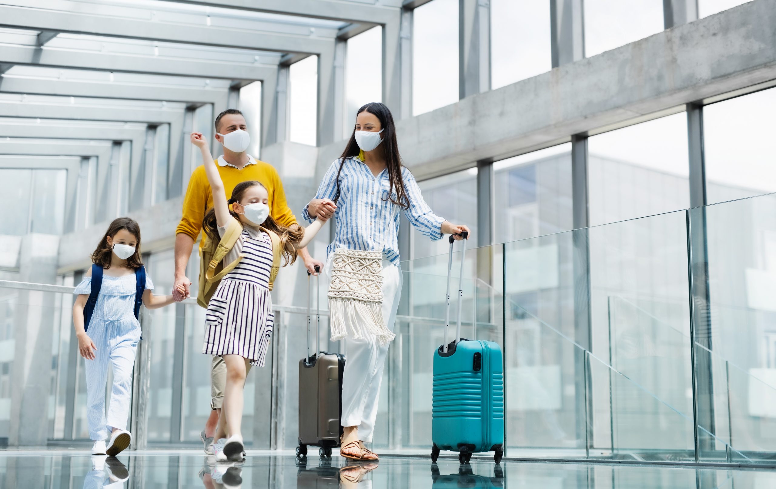 family-with-two-children-going-on-holiday-wearing-face-masks-at-the-airport-