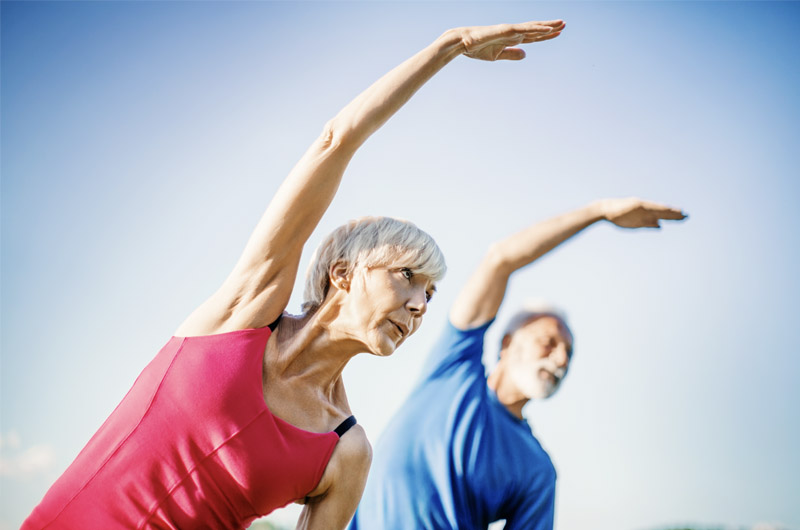 Dos personas mayores haciendo yoga. El yoga es una buena forma de mantener los músculos a medida que se envejece.