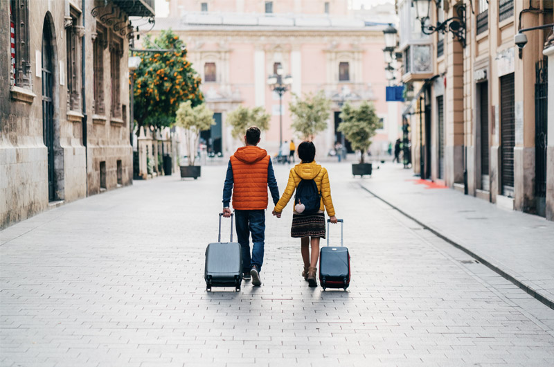 Un hombre y una mujer caminan con maletas. 2022 es un año de recuperación del turismo, pero ¿en cuánto?