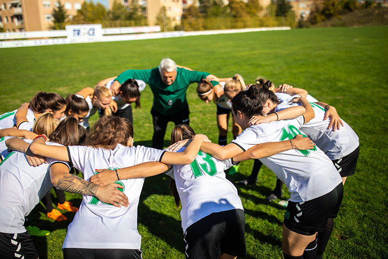 female-soccer-team-huddling-with-their-coach-before-training