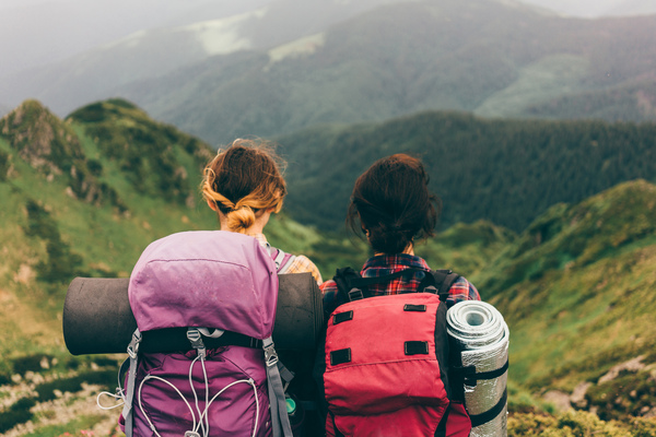 Dos personas haciendo turismo ambiental en una montaña con dos mochilas. 