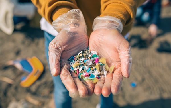 Unas manos mostrando microplásticos de la playa