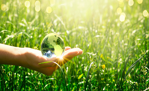 earth-crystal-glass-globe-in-human-hand-on-fresh-juicy-grass-background-saving-environment-and-clean-green-planet-concept-card-for-world-earth-day-
