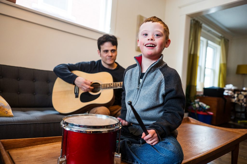 Niño con síndrome de down,  junto a su padre, tocando instrumentos. 