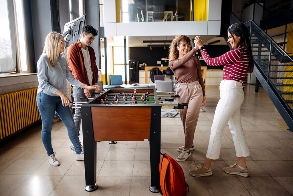 diseño inclusivo en la empresa: Empleados jugando en una mesa de futbolín.