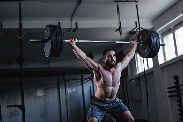 Un deportista haciendo levantamiento de pesas para mejorar su fuerza muscular. 